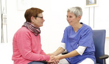 Pflegerin hält Hand der Patientin